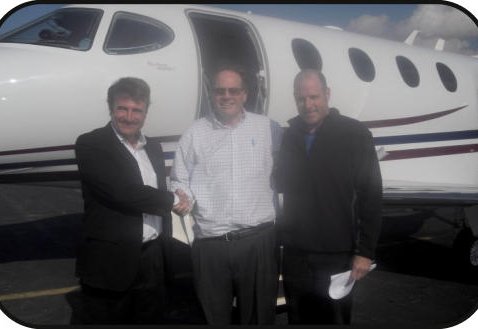 Three brokers beside a midsize jet